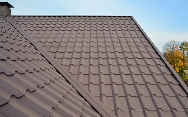 Metal roof construction with coaxial chimney pipe heating system against blue sky.